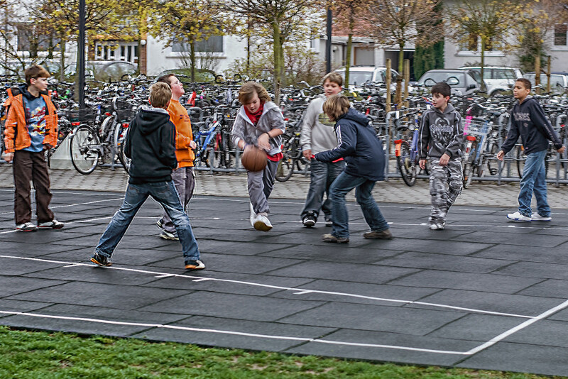 Un groupe adolescents joue au basket sur un terrain de basket extérieur fait de dalles vertes de jeu de ballon WARCO.