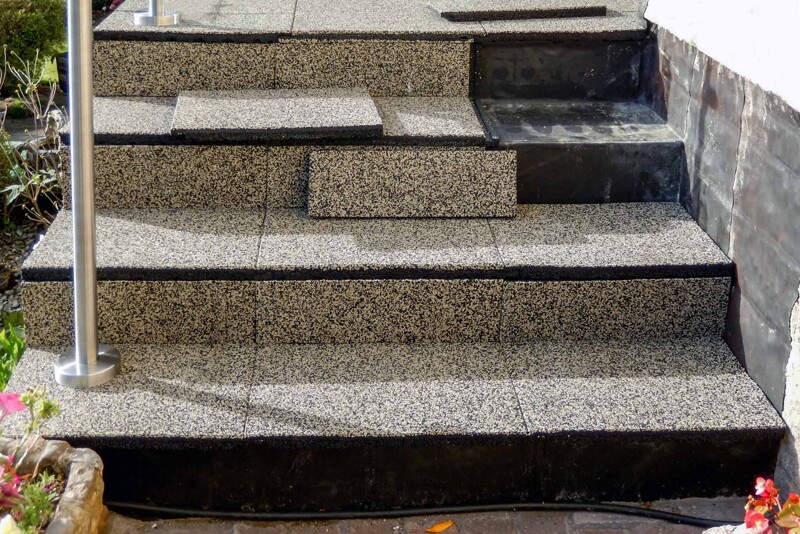 Un escalier en béton menant à une terrasse surélevée recouvert du revêtement WARCO. Trois éléments manquants seront collés.