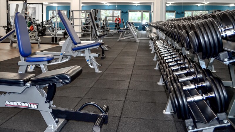 Dans une salle de musculation, plusieurs bancs inclinés pour entraînement des haltères sont placés sur un sol sportif WARCO