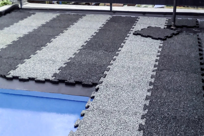 Une vieille piscine en béton dans le jardin est en cours de rénovation. Un entourage de piscine est couvert de dalles WARCO en Granit clair et Granit foncé.