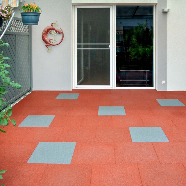 La terrasse de la maison moderne en rangée, avec des dalles en couleurs rouges et grise constitue un allongé du salon.